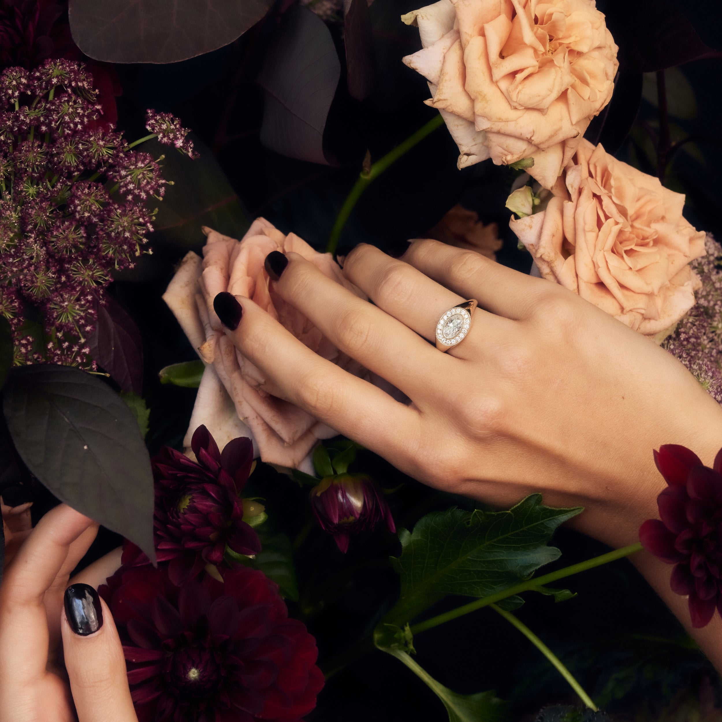 Antique oval moissanite signet ring with halo and milgrain floating in flowers