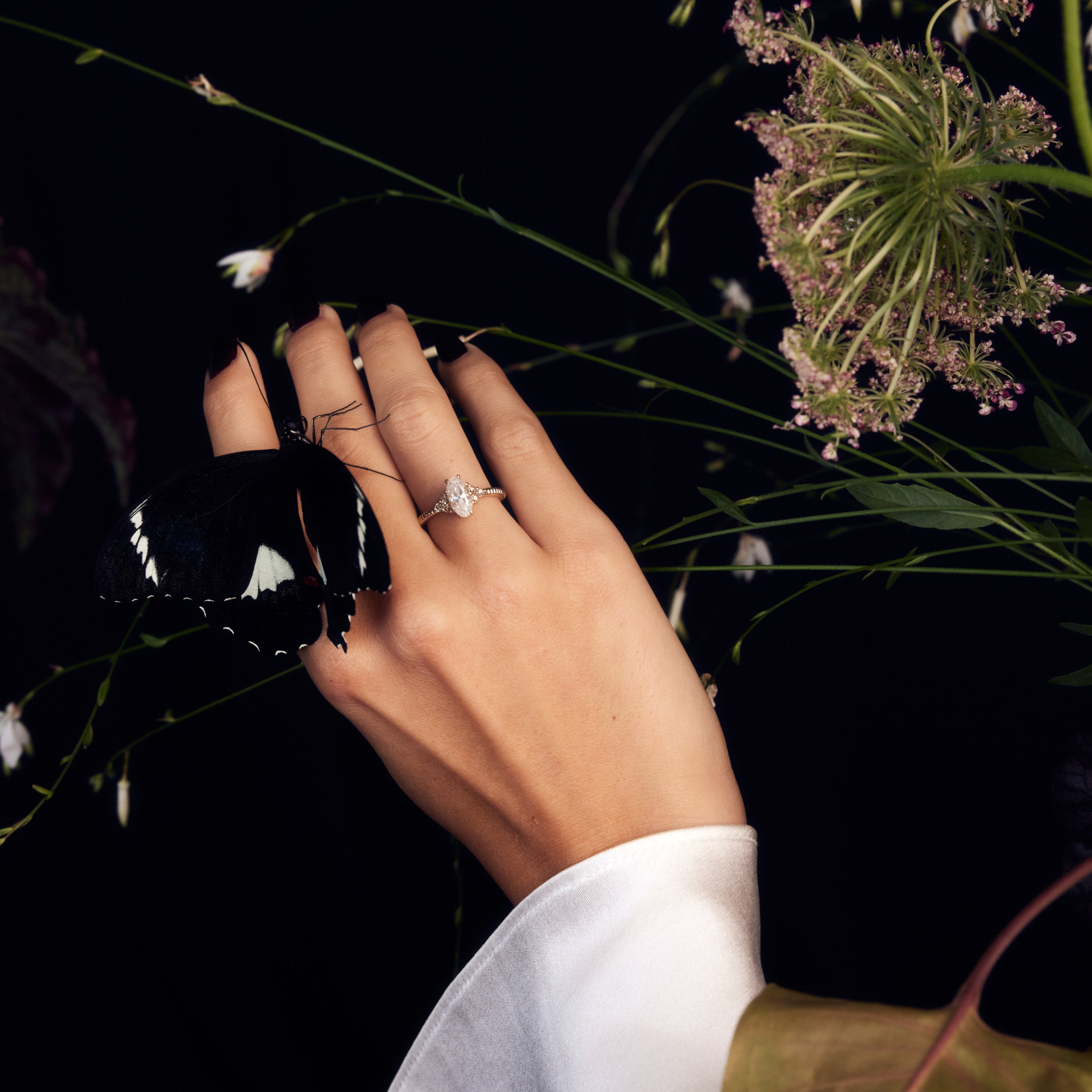 Oval moval moissanite cluster engagement ring champagne side stones antique cut fluted band on hand with butterfly and flowers on wedding day